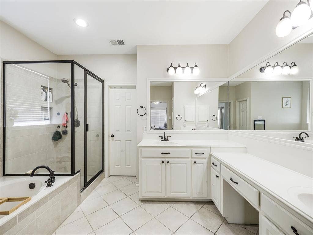 1206 Bel Air Drive, Allen, TX 75013 Black-framed glass shower enclosure, built-in soaking tub with black fixtures, dual white vanity with integrated sinks, expansive wall-mounted mirror, and tile flooring