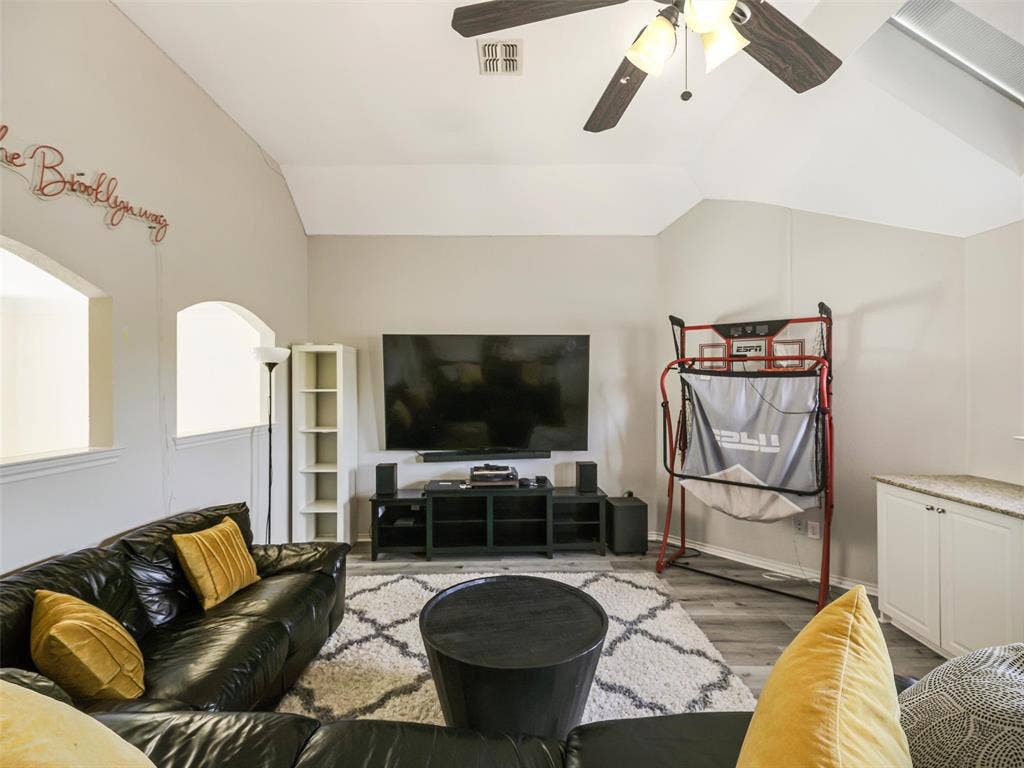 1206 Bel Air Drive, Allen, TX 75013 Vaulted ceiling with a ceiling fan light fixture, wood-finish flooring, built-in cabinetry with a stone-finish countertop, and arched openings
