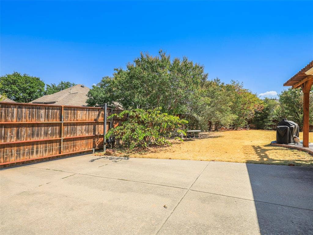 1206 Bel Air Drive, Allen, TX 75013 Expansive backyard with a concrete patio, wood fence, and mature trees