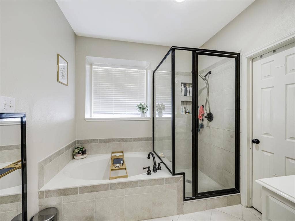 1206 Bel Air Drive, Allen, TX 75013 Built-in soaking tub with tiled surround, separate glass-enclosed shower with tiled walls, and window with blinds