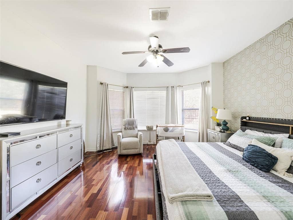 1206 Bel Air Drive, Allen, TX 75013 Rich wood-finish flooring, ceiling fan with integrated lighting, bay window, and accent wall with geometric pattern