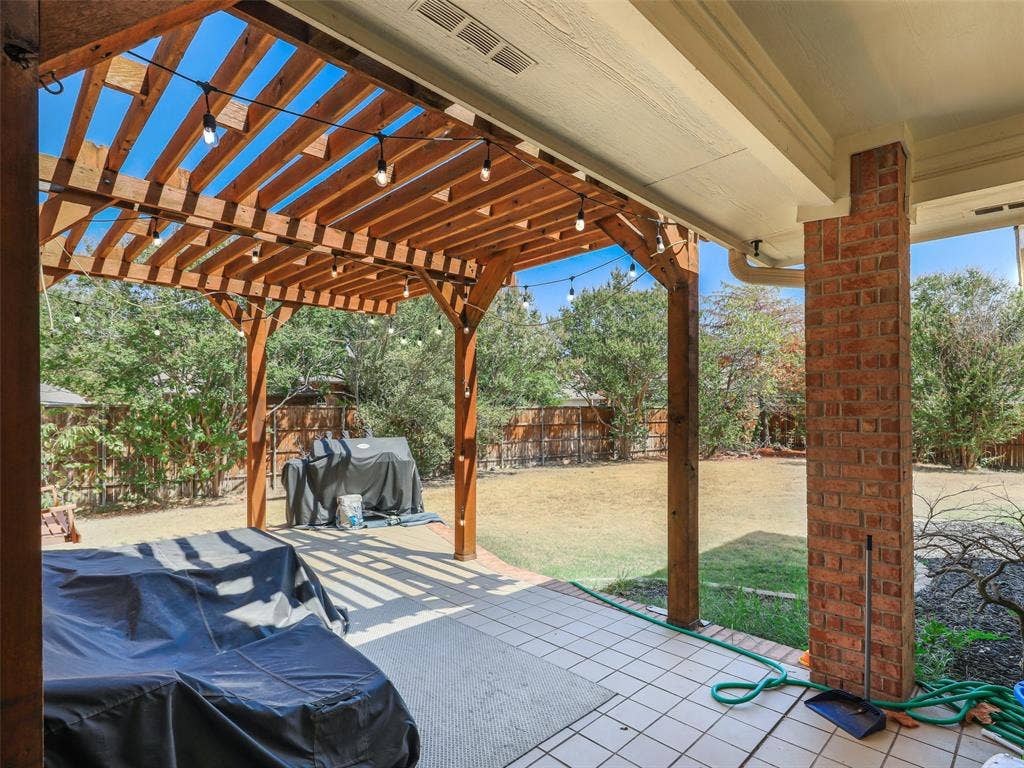 1206 Bel Air Drive, Allen, TX 75013 Expansive outdoor living area featuring a wood pergola with string lights, brick column accents, and a tiled patio surface