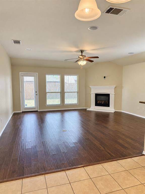 9609 Sand Trap Drive, McKinney, TX 75072 Spacious living area featuring wood-finish flooring, a ceiling fan, three windows, and a fireplace with a white mantel