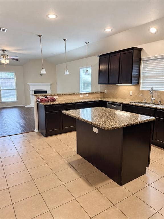 9609 Sand Trap Drive, McKinney, TX 75072 Kitchen featuring a central island, dark wood-finish cabinetry, granite countertops, and tile flooring