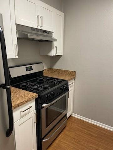 2200 W Lowden Street, #22, Fort Worth, TX 76110 Stainless steel range with oven, white upper and lower cabinetry, wood-finish flooring, and light-toned countertops