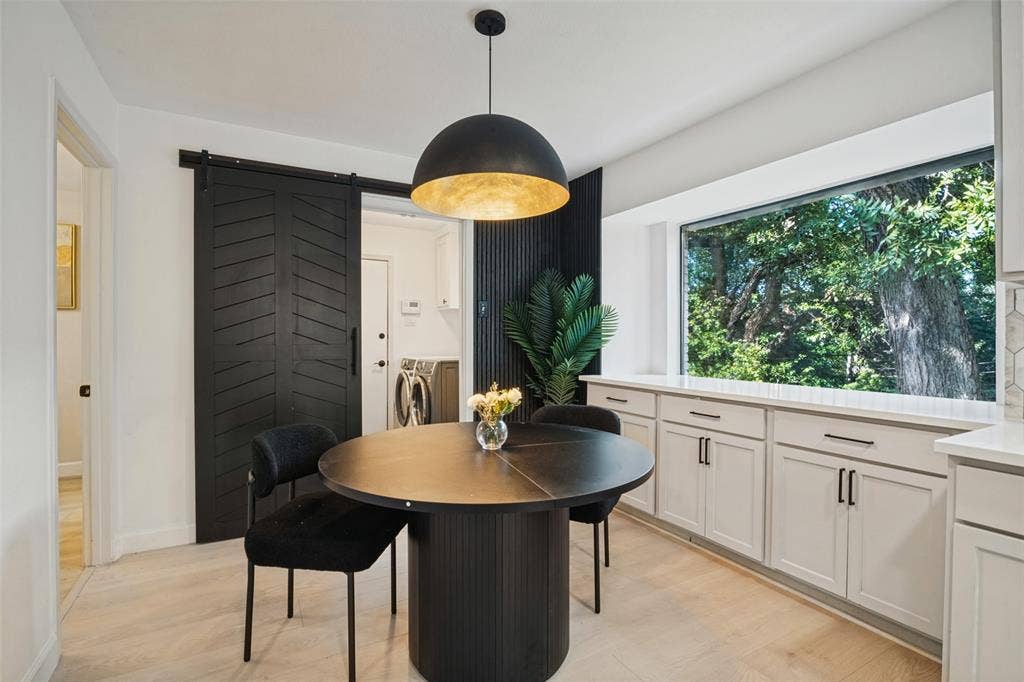 5021 Ashbrook Road, Dallas, TX 75227 Wood-finish flooring with a modern black barn door, a contemporary dome pendant light, integrated window bench seating, and white cabinetry with dark hardware