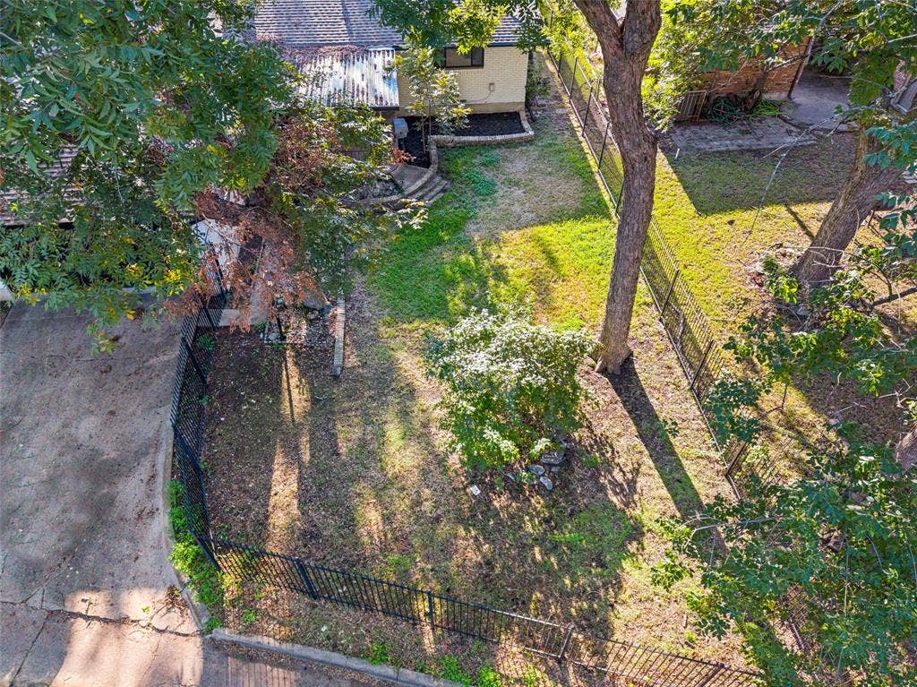 5021 Ashbrook Road, Dallas, TX 75227 Rear yard featuring mature trees, a black metal fence, and a concrete pathway