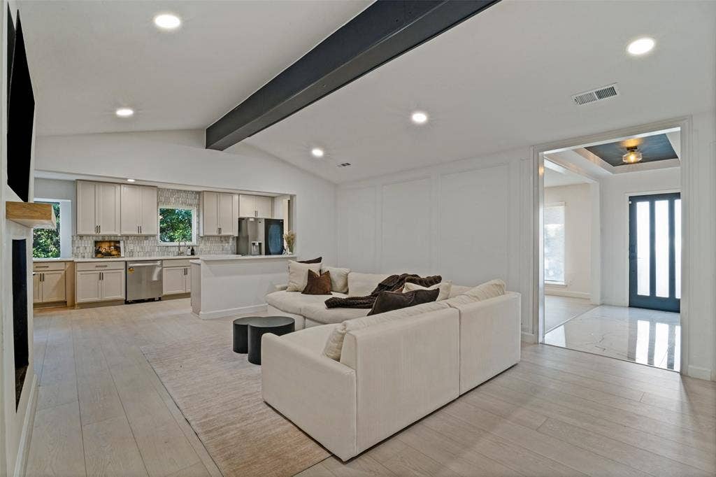 5021 Ashbrook Road, Dallas, TX 75227 Vaulted ceiling with an exposed beam, light wood-finish flooring, recessed lighting, and a modern kitchen with stainless steel appliances and light cabinetry