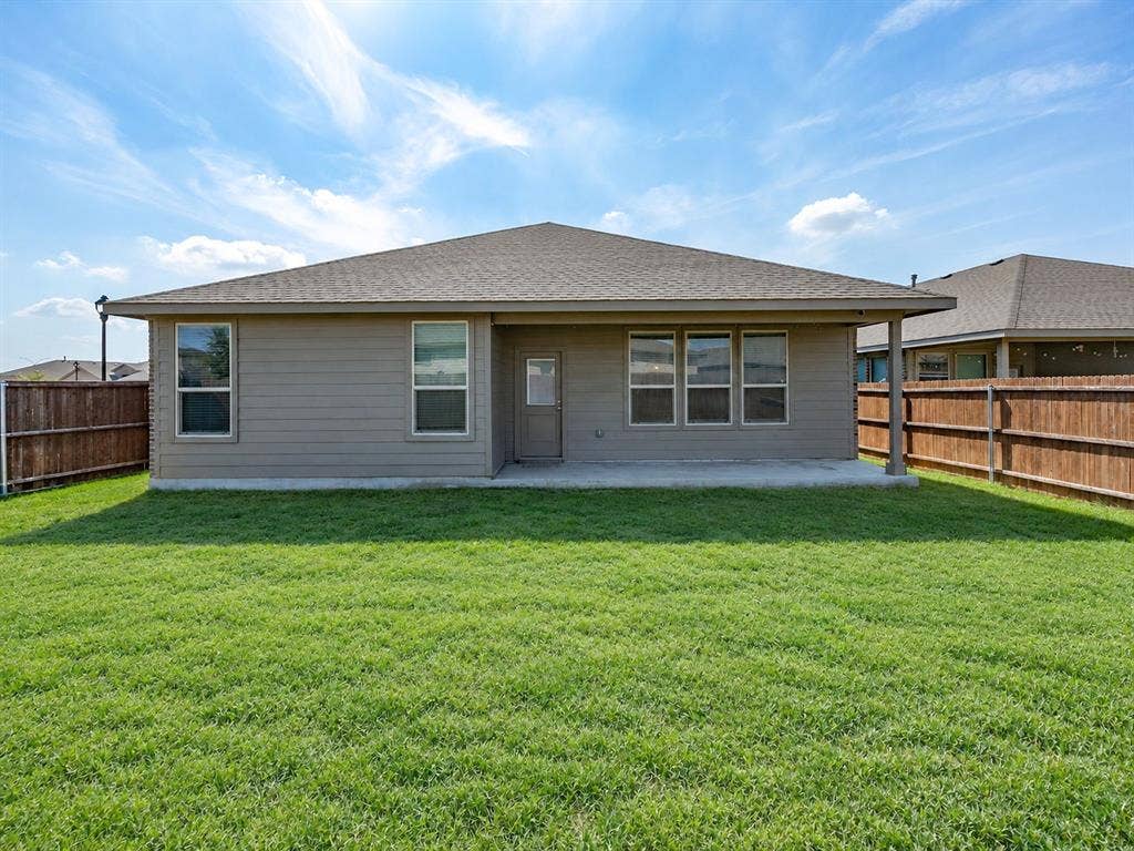 Expansive backyard featuring a manicured lawn, a concrete patio, and a covered patio area