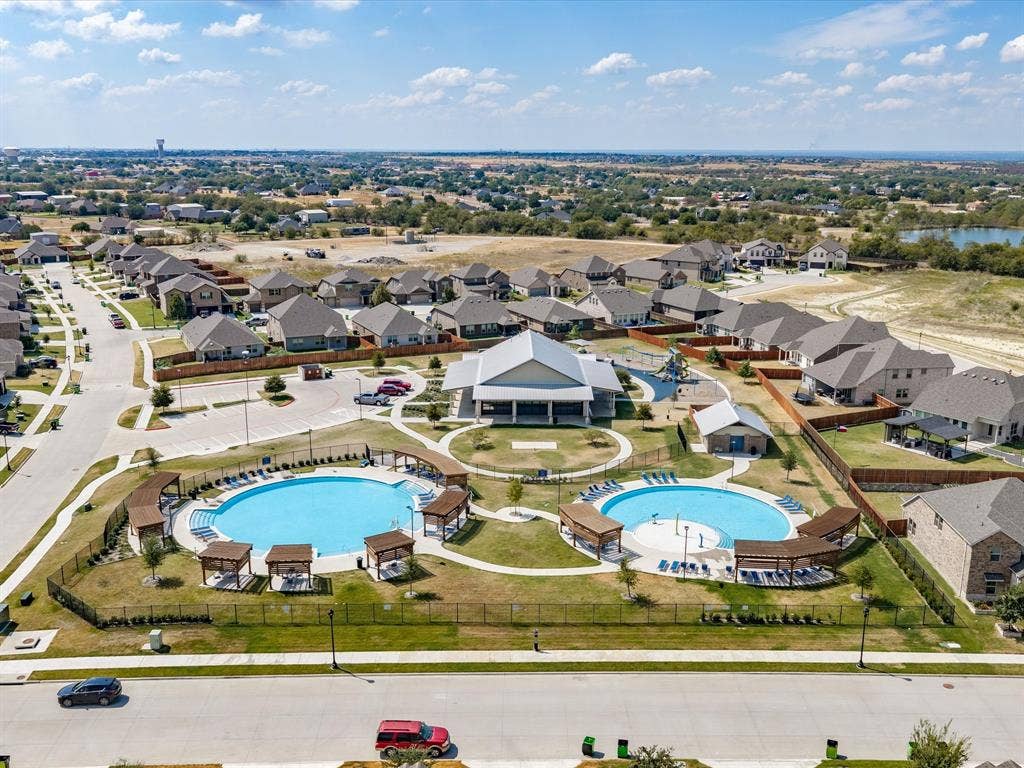 Community pool with multiple lounge areas, a splash pad, and a recreational building