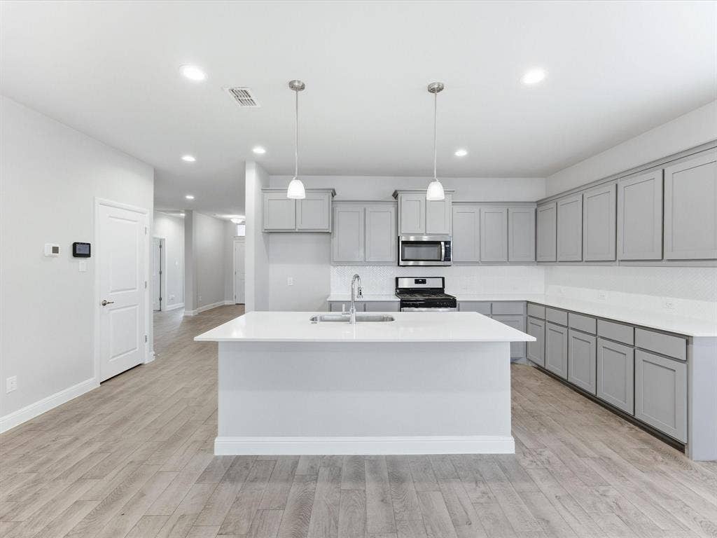 Kitchen featuring an expansive island, light gray cabinetry, white countertops, wood-finish flooring, and recessed lighting