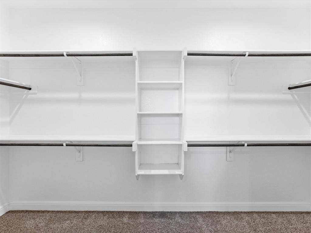 Built-in closet shelving system with multiple hanging rods and integrated vertical storage