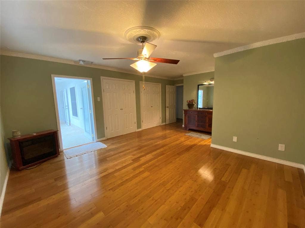 1608 University Drive, Richardson, TX 75081 Unfurnished bedroom featuring ornamental molding, wood finished floors, multiple closets, baseboards, and ceiling fan