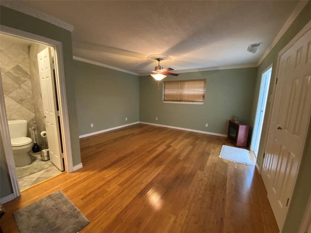 1608 University Drive, Richardson, TX 75081 Unfurnished bedroom with ornamental molding, wood finished floors, baseboards, ceiling fan, and connected bathroom