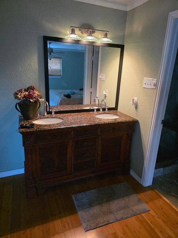1608 University Drive, Richardson, TX 75081 Bathroom featuring double vanity, ensuite bath, wood finished floors, and a sink