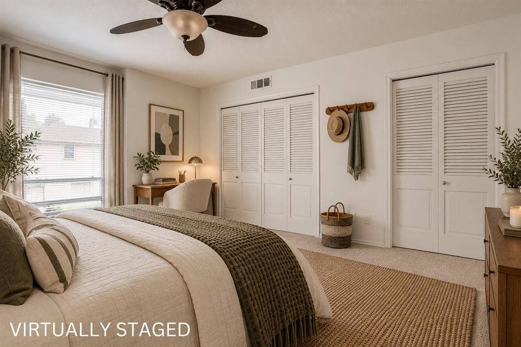 Ceiling fan, window with blinds, two louvered bifold closet doors, and carpet flooring