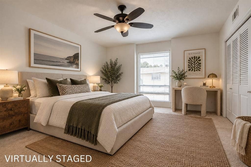 Integrated ceiling fan, neutral wall tones, large window with blinds, louvered closet doors, and wood-finish desk area