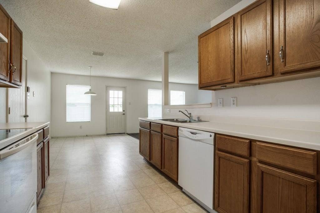 2800 Bissell Way, Wylie, TX 75098 Kitchen featuring wood-finish cabinetry, white countertops, a built-in dishwasher, and a stainless steel sink