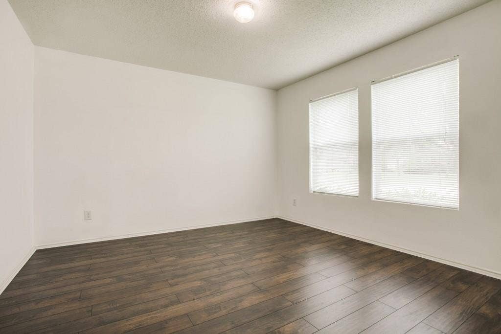 2800 Bissell Way, Wylie, TX 75098 Wood-finish flooring with white walls, two windows with blinds, and a ceiling-mounted light fixture