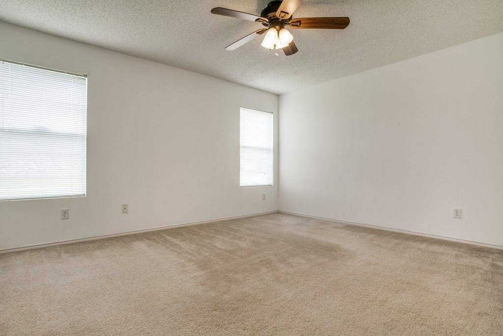 2800 Bissell Way, Wylie, TX 75098 Spacious room featuring neutral carpeting, white walls, two windows with blinds, and a ceiling fan with integrated lighting