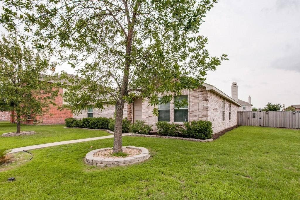 2800 Bissell Way, Wylie, TX 75098 Brick exterior, mature trees with stone-lined bases, green lawn, established landscaping, and a privacy fence