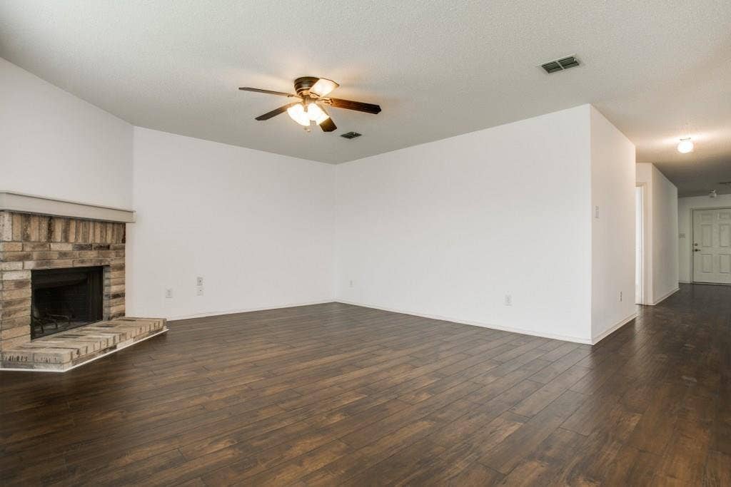 2800 Bissell Way, Wylie, TX 75098 Expansive living area featuring wood-finish flooring, a brick-surround fireplace with hearth, and a ceiling fan