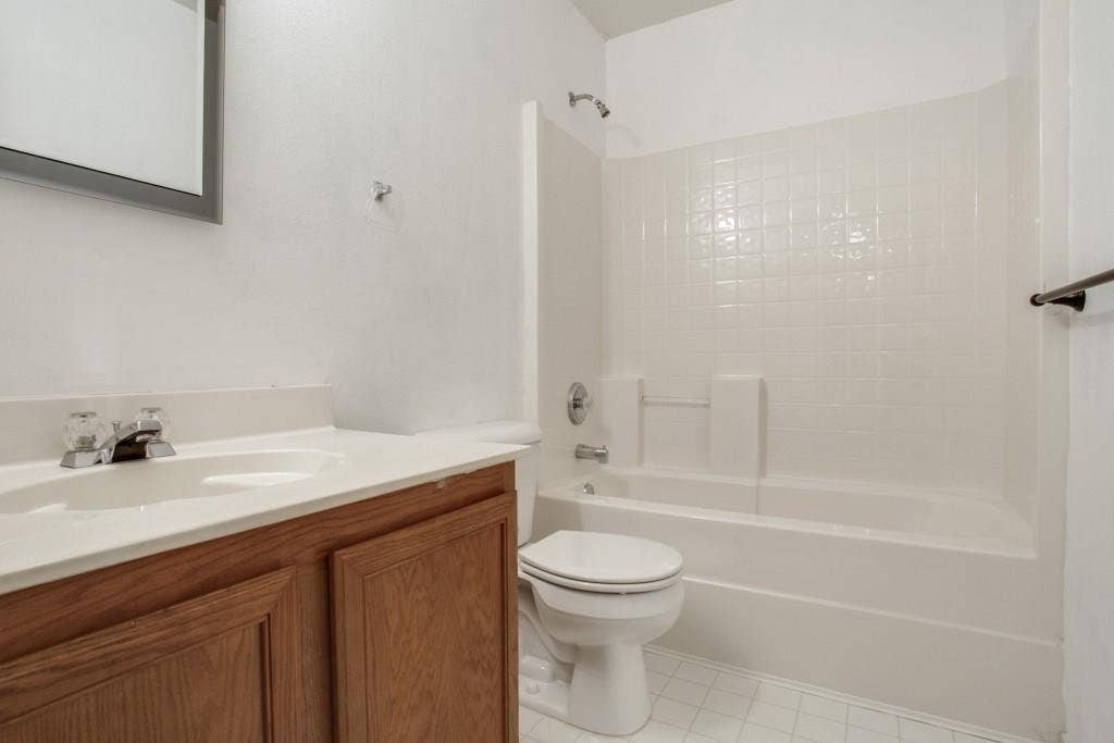 2800 Bissell Way, Wylie, TX 75098 Bathroom featuring a wood-finish vanity with an integrated sink, a white countertop, and a white tiled shower/tub combination