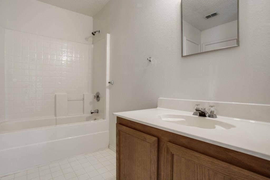 2800 Bissell Way, Wylie, TX 75098 White subway tile tub surround, chrome fixtures, built-in vanity with wood-finish cabinetry, white countertop, and tile flooring