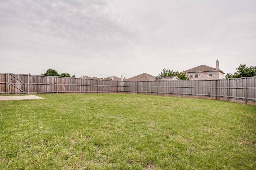 2800 Bissell Way, Wylie, TX 75098 Expansive grass lawn bordered by a wood privacy fence with a gated entry