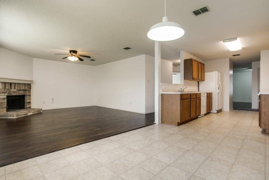 2800 Bissell Way, Wylie, TX 75098 Living area with wood-finish flooring, a stone-faced fireplace, and a ceiling fan