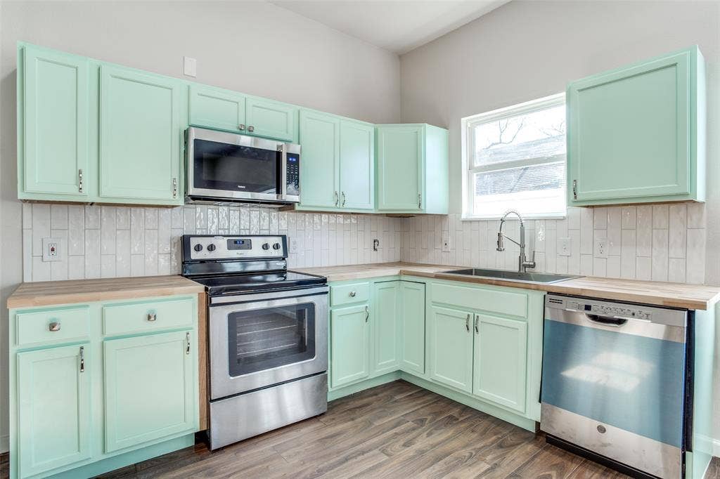 2316 Marburg Street, Dallas, TX 75215 Kitchen featuring decorative backsplash, a sink, wood counters, appliances with stainless steel finishes, and wood finished floors