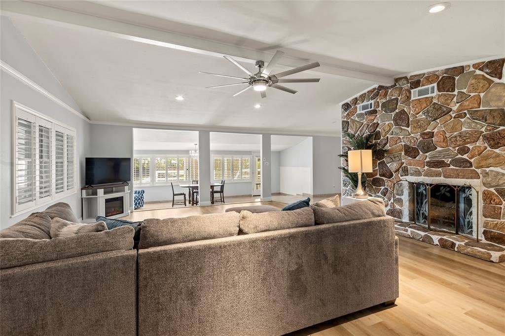 110 Henderson Harbor Circle, Payne Springs, TX 75156 Vaulted ceiling with exposed beams, wood-finish flooring, stone-clad fireplace with hearth, recessed lighting, and white plantation shutters