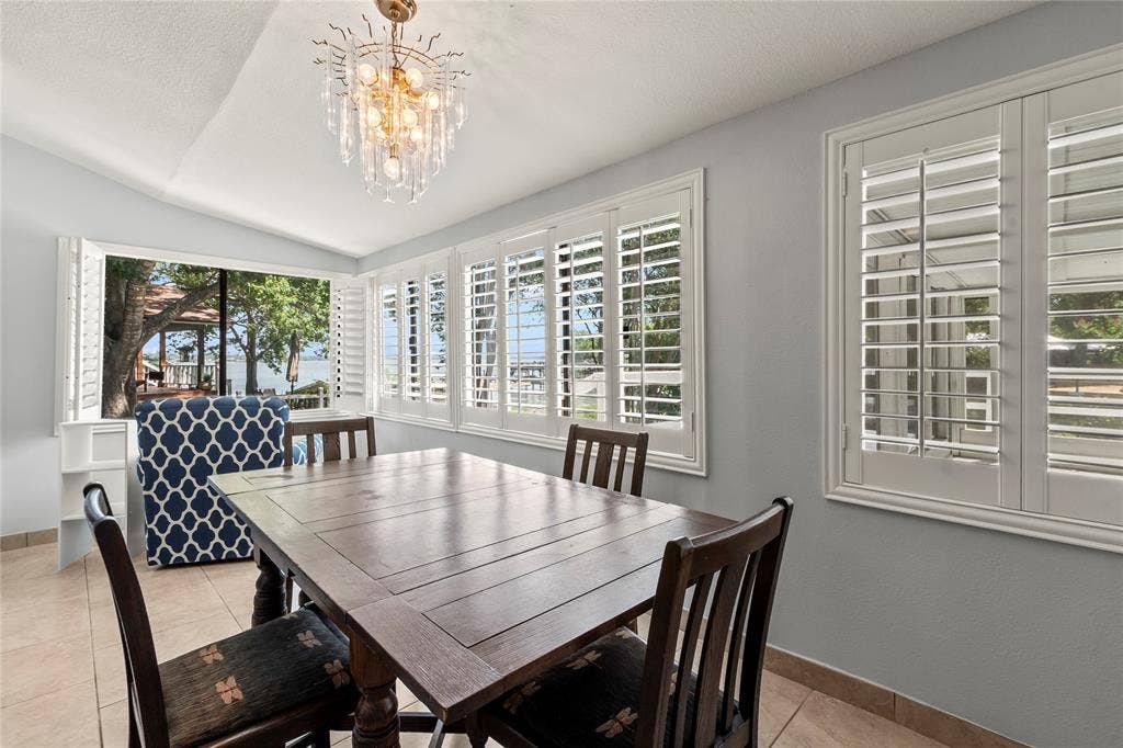 110 Henderson Harbor Circle, Payne Springs, TX 75156 Tray ceiling with a decorative chandelier, multiple windows with white plantation shutters, and light-toned tile flooring