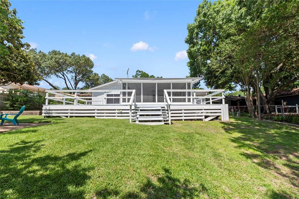 110 Henderson Harbor Circle, Payne Springs, TX 75156 Spacious rear yard with a sloped lawn, a large wood deck with railings, and a screened-in porch