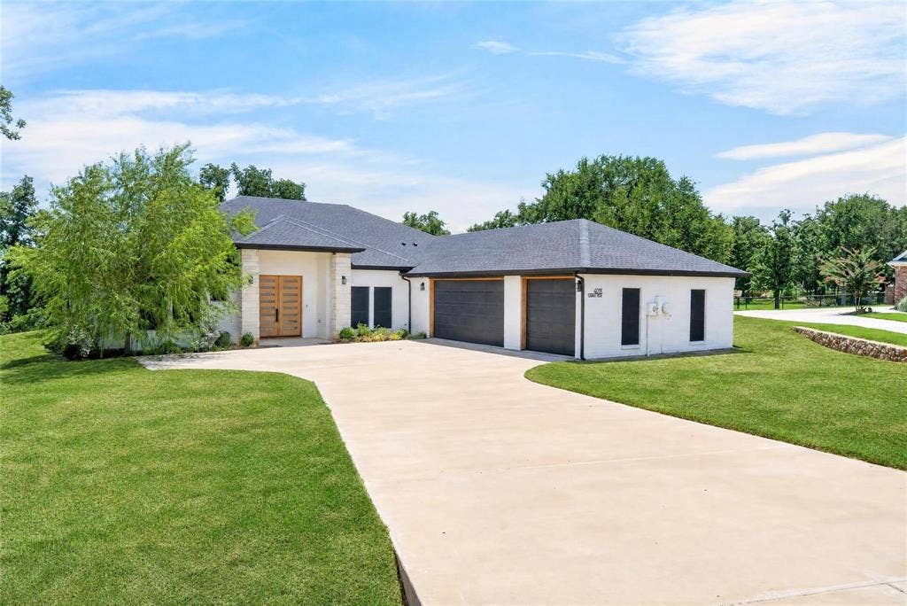 Contemporary exterior with a white brick finish, dark roofing, and a prominent wood-panel double entry door