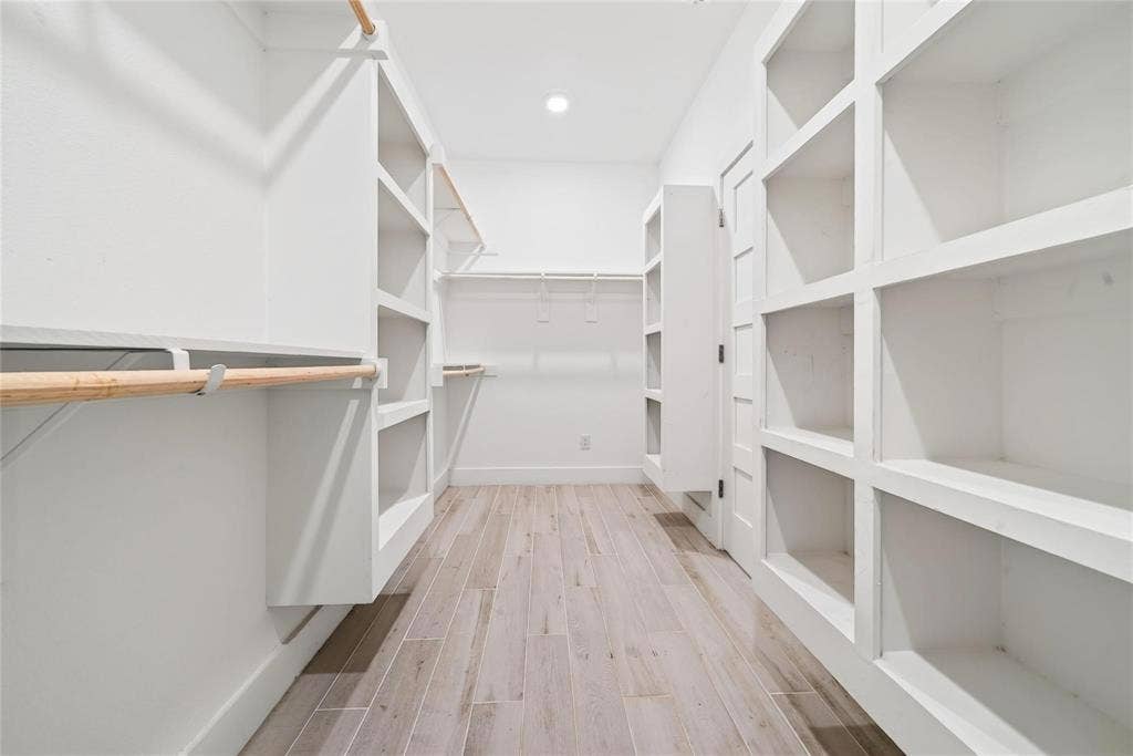 Walk-in closet featuring built-in shelving, wood-finish flooring, and recessed ceiling lighting
