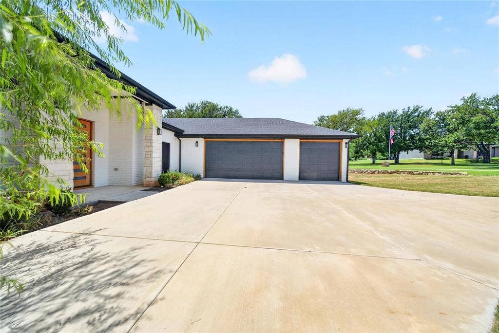 Exterior featuring a light-colored stucco and stone facade, a multi-panel wood-finish entry door, and a two-car garage with dark paneled doors