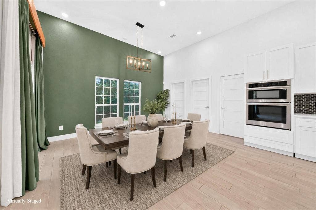 Vaulted ceiling, recessed lighting, wood-finish flooring, white shaker cabinetry, and stainless steel double ovens