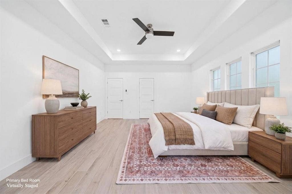 Tray ceiling with recessed lighting and a ceiling fan, wood-finish flooring, and multiple windows