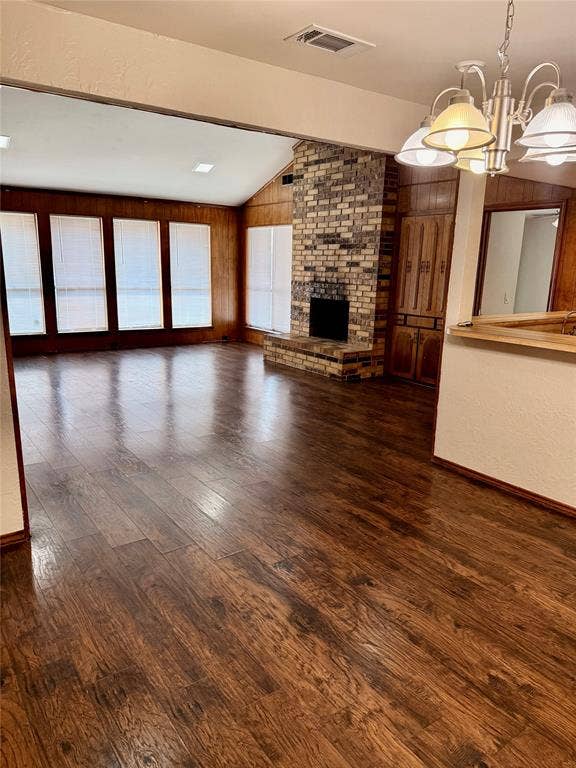 Open living area with fireplace, wall of windows and vaulted ceiling.