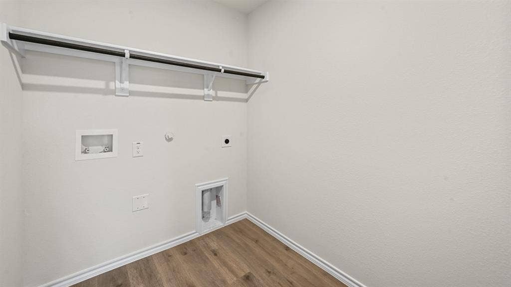 810 Parksville Drive, Ferris, TX 75125 Laundry area featuring wood-finish flooring, white walls, and a built-in hanging rod
