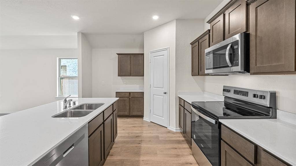 810 Parksville Drive, Ferris, TX 75125 Kitchen featuring wood-finish flooring, stainless steel appliances, white countertops, and dark wood cabinetry