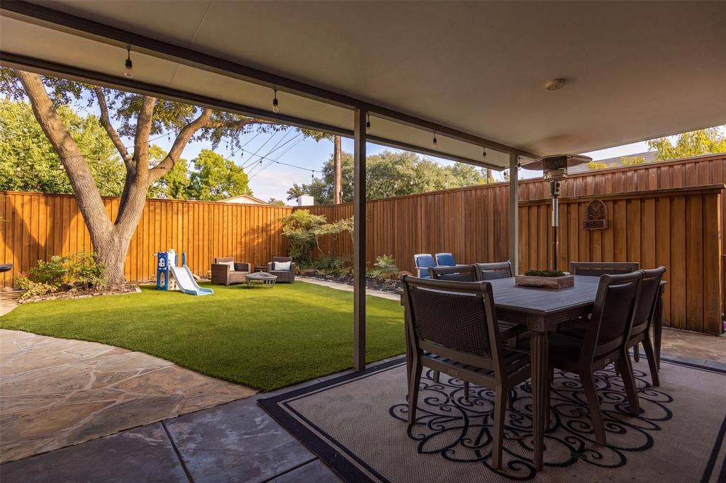 10945 Middle Knoll Drive, Dallas, TX 75238 Expansive covered patio with concrete and flagstone finishes, artificial turf, and wood privacy fencing