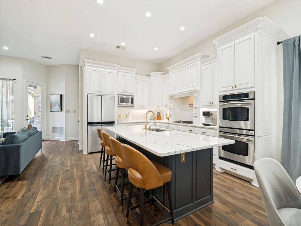 Kitchen features an expansive island, granite countertops, recessed lighting, double ovens and plenty of cabinets.