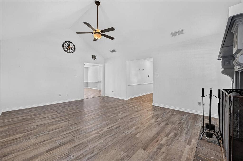 Vaulted ceiling with a ceiling fan, wood-finish flooring, and a decorative fireplace
