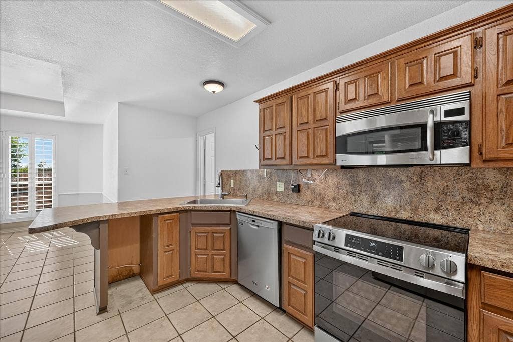 Kitchen featuring wood cabinetry, stainless steel appliances, a built-in microwave, and a tile backsplash