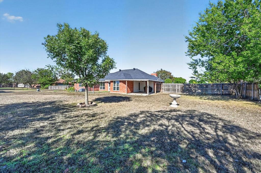 Expansive backyard featuring a brick exterior, covered patio, and perimeter fencing