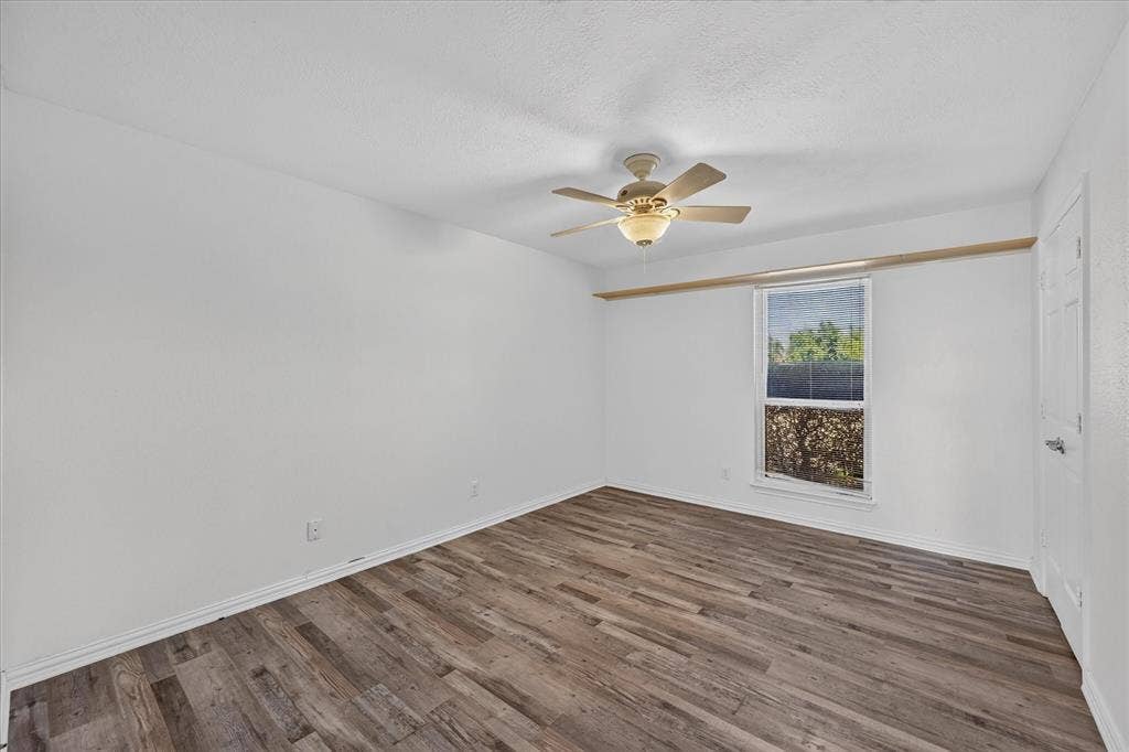 Ceiling fan with integrated lighting, wood-finish flooring, white painted walls, and a window with blinds