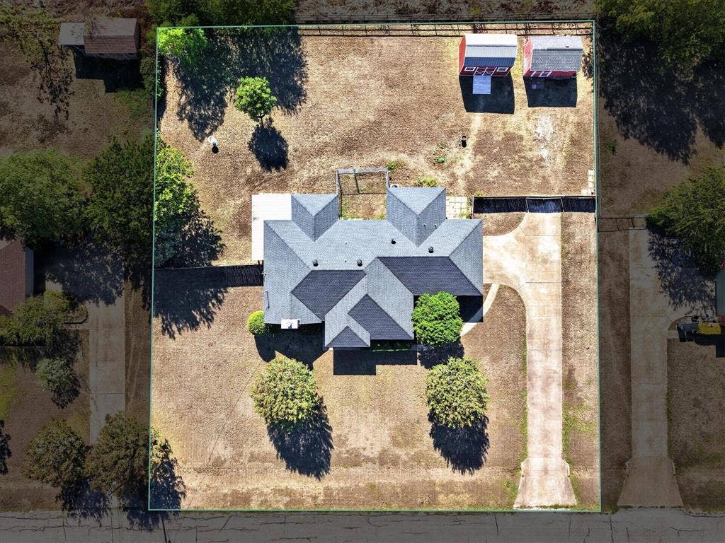 Expansive lot featuring a main residence with a multi-gabled roof, a concrete driveway, and two detached outbuildings
