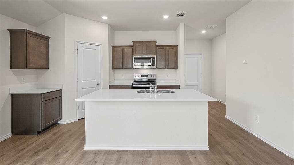215 Yates Street, Bullard, TX 75757 Open-concept kitchen featuring an expansive central island, wood-finish flooring, recessed lighting, and stainless steel appliances